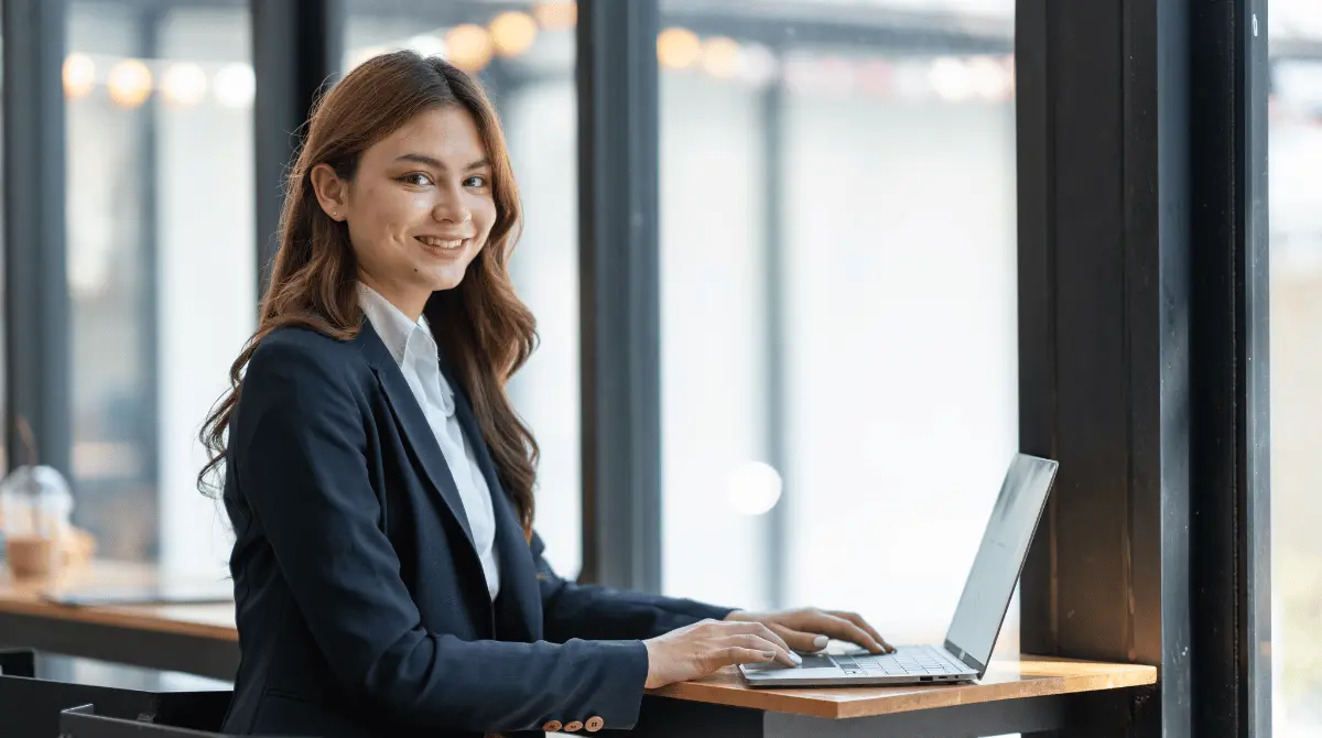 A professional data entry virtual assistant smiling while working on a laptop.